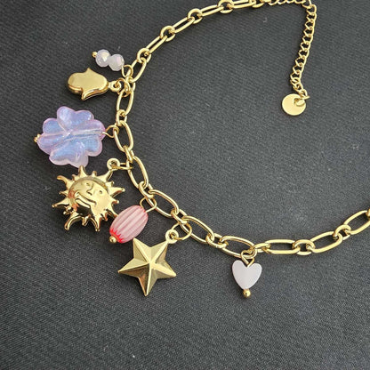 Bracelet Doré à Maillons Ovales Orné de Charms Célestes et Trèfles à Quatre Feuilles Roses